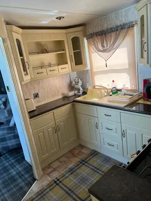 a kitchen with white cabinets and a sink and a window at 47 Lochview in Stranraer