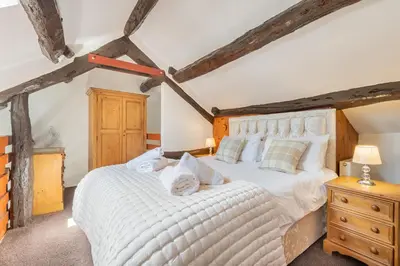 a bedroom with a large white bed and wooden ceilings at Cottage 1, Old Farmhouse Mews in Braithwaite