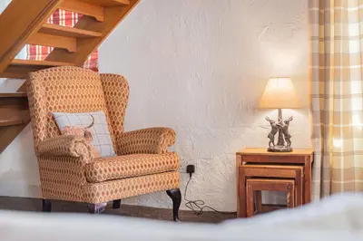 a chair sitting next to a table with a lamp at Cottage 1, Old Farmhouse Mews in Braithwaite