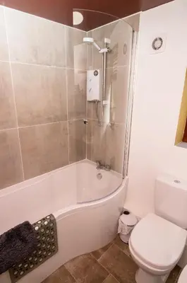 a bathroom with a white tub and a toilet at Maltings House Cosy and Stylish 2 bedroom flat near the city centre with free parking and ensuite rooms in Carlisle
