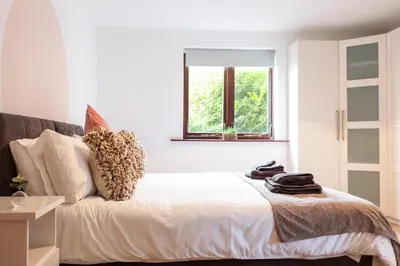 a bedroom with a bed with a window at Maltings House Cosy and Stylish 2 bedroom flat near the city centre with free parking and ensuite rooms in Carlisle