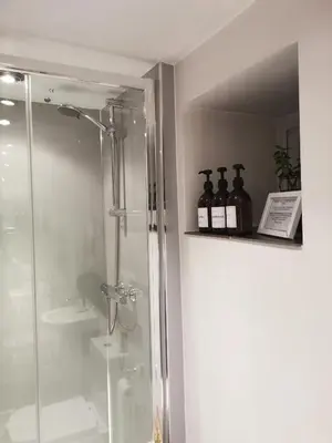 a bathroom with a shower and bottles on a shelf at Mill Cottage modern cosy Lake District home with open fire near Scafell in Gosforth