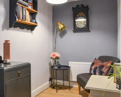 a living room with a couch and a clock on the wall at Mill Cottage modern cosy Lake District home with open fire near Scafell in Gosforth