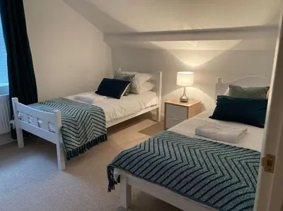 a bedroom with two beds and a lamp in it at Marni’s Cottage - Rural location & fell views in Frizington