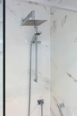 a shower in a bathroom with white marble walls at West Sands - Donnini Apartments in Ayr