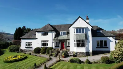 a white house with a red door and a yard at Dalegarth House Portinscale in Keswick