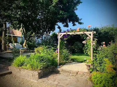 a garden with a wooden arch and some plants at The Sty & The Stable in Carlisle