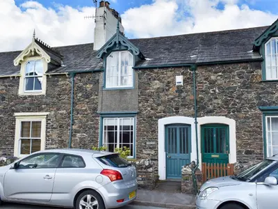 a stone house with two cars parked in front of it at Hey Down in Keswick