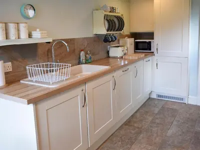 a kitchen with white cabinets and a sink at Hey Down in Keswick