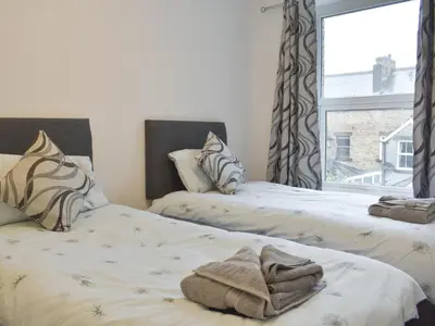 two beds with towels on them in a room with a window at Helvellyn House in Keswick