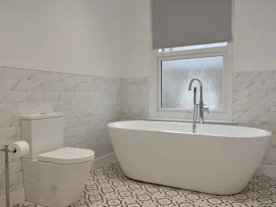 a white bathroom with a bath tub and a window at Helvellyn House in Keswick