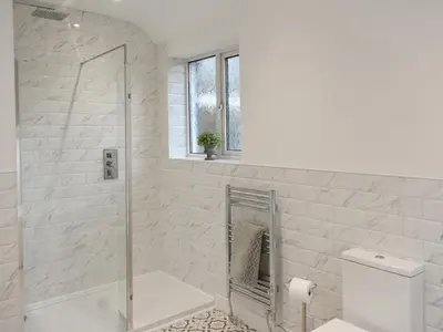 a white bathroom with a shower and a toilet at Helvellyn House in Keswick