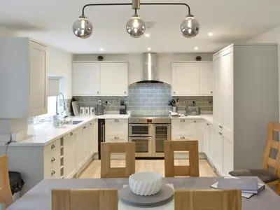 a kitchen with white cabinets and a table with chairs at Helvellyn House in Keswick