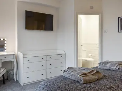 a bedroom with a bed and a dresser with a tv on the wall at Helvellyn House in Keswick