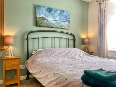 a bedroom with a bed and a painting on the wall at Kerrim Cottage in Ringford