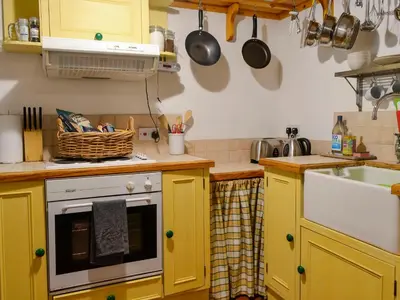 a kitchen with yellow cabinets and a sink at Church Cottage in Rigg