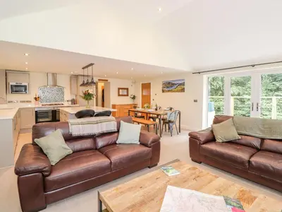 a living room with two brown leather couches and a kitchen at Ladstock Cottage in Keswick