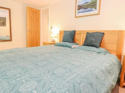 a bedroom with a large bed with a blue comforter at Ladstock Cottage in Keswick