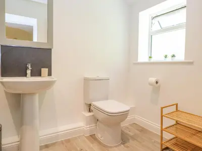 a white bathroom with a toilet and a sink at Ladstock Cottage in Keswick