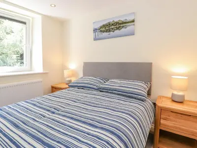 a bedroom with a bed with a blue and white striped comforter at Ladstock Cottage in Keswick