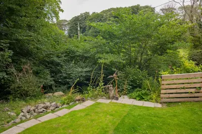 a garden with a bench in the grass at Tig Cottage - a rural, quirky, pet friendly 2 bedroom cottage near Ballantrae in Ballantrae