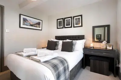 a bedroom with a large bed with two towels on it at Jontys Cottage in Ambleside