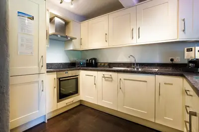 a kitchen with white cabinets and a sink at Jontys Cottage in Ambleside