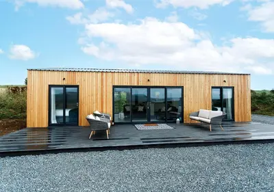 a wooden house with two chairs on a wooden deck at Sea Glass Lodge in Gatehouse of Fleet