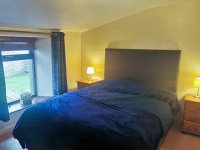 a bedroom with a large bed and a window at The Moorings in Lochmaben