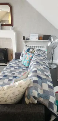a bed with a blue and white blanket on it at Cosy apartment in popular harbour town in Kirkcudbright