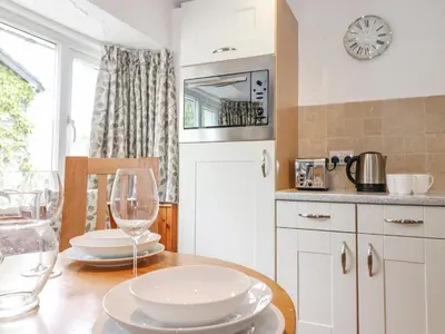a kitchen with a table with plates and wine glasses at Woodloft Cottage in Elterwater
