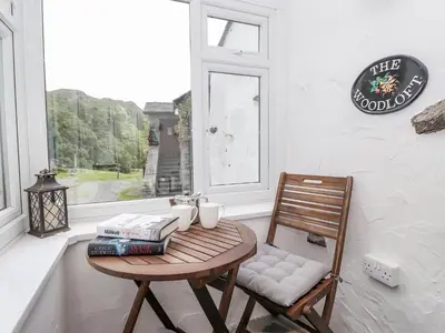 a table and a chair in a room with a window at Woodloft Cottage in Elterwater
