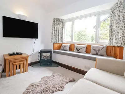 a living room with a couch and a window at Woodloft Cottage in Elterwater