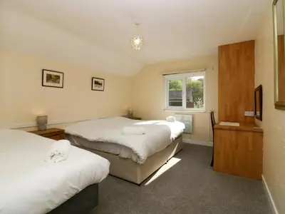 a bedroom with three beds and a window at Newfield Apartment 1 in Broughton in Furness