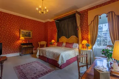 a bedroom with a bed and orange wallpaper at Glenapp Castle in Ballantrae