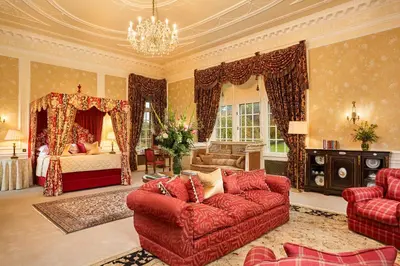 a living room with a red couch and a bed at Glenapp Castle in Ballantrae