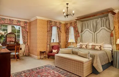a bedroom with a bed and a chair and a piano at Glenapp Castle in Ballantrae