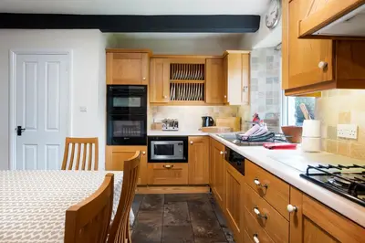 a kitchen with wooden cabinets and a table with a counter top at Oak Cottage Chapel Stile in Chapel Stile