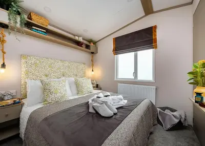 a bedroom with a large bed with towels on it at Heads Of Ayr Holiday Park in Ayr