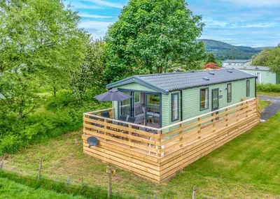 a small green tiny house with a roof at Sandgreen Caravan Park in Girthon