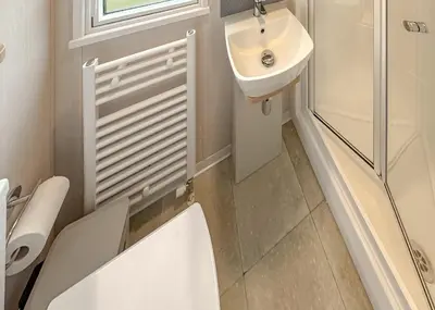 a white bathroom with a toilet and a sink at Sandgreen Caravan Park in Girthon