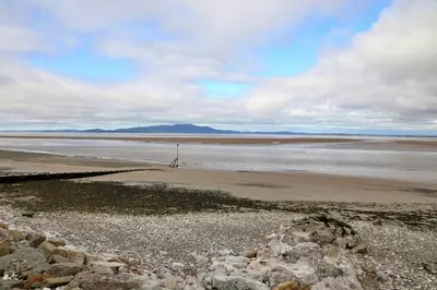 a beach with a body of water and some rocks at Finest Retreats - Glendale in Skinburness