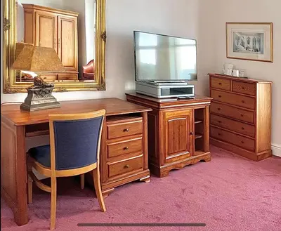 a room with a desk with a television on a dresser at Promenade House in Douglas