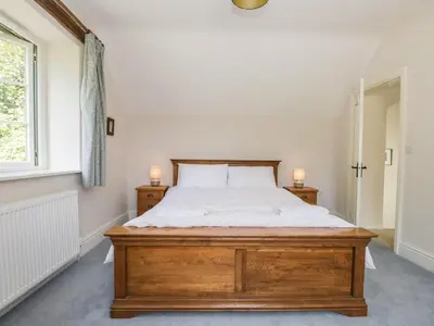 a bedroom with a wooden bed and a window at Caldhu Cottage in Holmrook