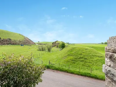 a road through a green field with sheep in the distance at The Railway Sleeper in Hyndfordbridge-end