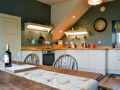 a kitchen with a wooden table and a dining room at The Old Vicarage in Westward
