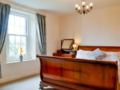 a bedroom with a bed with a mirror and a window at The Old Vicarage in Westward