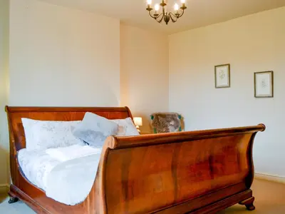 a bedroom with a wooden bed and a chandelier at The Old Vicarage in Westward