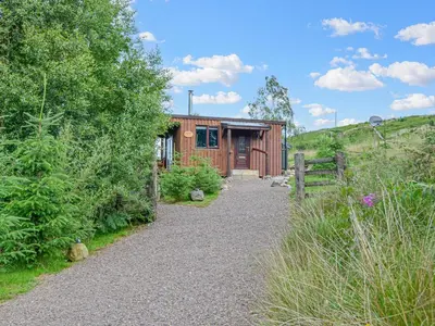 a small wooden cabin with a gravel path leading to it at Glenkens Lodge in Dalry