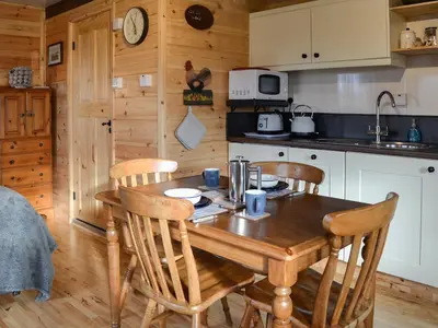 a kitchen with a wooden table and four chairs at Glenkens Lodge in Dalry